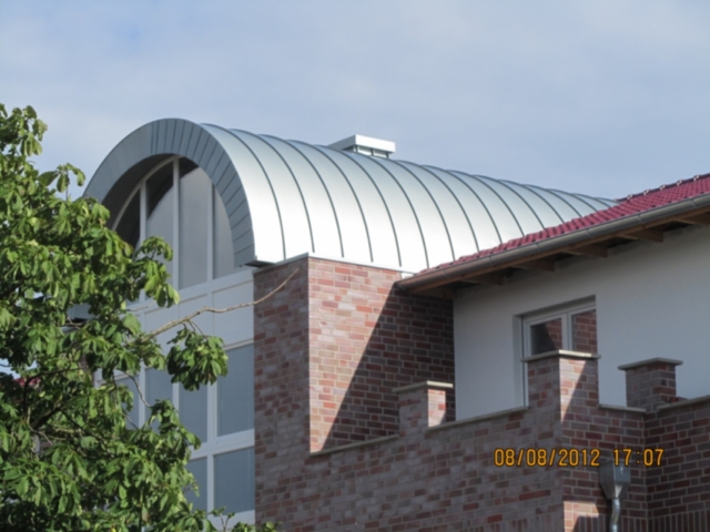 Gebäude mit einem großen, runden, silbernen Dach und einer Ziegelfassade.